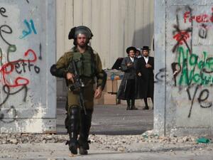 Orthodox Jewish men stand behind Israel's controversial separation barrier as a soldier makes his way through the West Bank entrance to Bethlehem, October 12, 2015. (AFP/File) Orthodox Jewish men stand behind Israel's controversial separation barrier as a soldier makes his way through the West Bank entrance to Bethlehem, October 12, 2015. (AFP/File)