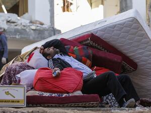 An Iranian man rests as he lies atop salvaged mattresses and items outside damaged buildings in the town of Sarpol-e Zahab near the border with Iraq following a 7.3-magnitude earthquake that left hundreds killed and thousands homeless. 
(ATTA KENARE / AFP)