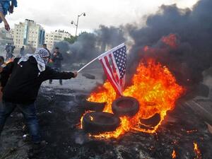 A Palestinian protester sets alight an America flag during clashes with Israeli troops at a protest against President Trump's decision to recognize Jerusalem as the capital of Israel. (ABBAS MOMANI / AFP)