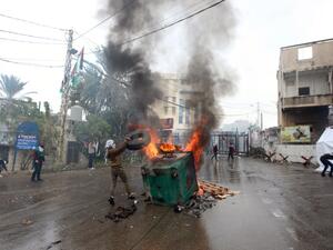 A protester throws a tire on a fire during a demonstration outside the US embassy in Awkar, on the outskirts of the Lebanese capital Beirut, on Dec. 10, 2017, to protest against Washington's decision to recognize Jerusalem as the capital of Israel (ANWAR AMRO/AFP)