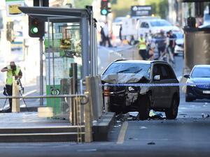 A white SUV (C) sits in the middle of the road as police and emergency personnel work at the scene of where a car ran over pedestrians in Flinders Street in Melbourne on Dec. 21, 2017 (Mal Fairclough / AFP)