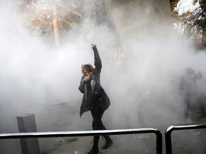 An Iranian woman raises her fist amid the smoke of tear gas at the University of Tehran during a protest driven by anger over economic problems in the capital Tehran on Dec. 30, 2017 (STR / AFP)