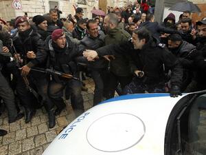 Palestinian policemen push away protesters from the convoy of Jerusalem's Greek Orthodox Patriarch Theophilos III outside the church of Nativity in the West Bank town of Bethlehem on Jan. 6, 2018 ahead of a Christmas service according to the Eastern Orthodox calendar (MUSA AL SHAER/AFP)