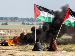 Palestinian protesters wave their national flag near the Israel-Gaza border east of the southern Gaza Strip city of Khan Yunis as they demonstrate against calls for the closure of UNRWA on Jan. 9, 2018 (SAID KHATIB / AFP)