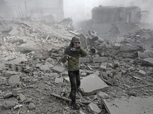 A Syrian girl appears from the rubble holding her shoe following an air strike on Hamouria, in the besieged rebel-held Eastern Ghouta area near Damascus, on Jan. 9, 2018 (ABDULMONAM EASSA / AFP)