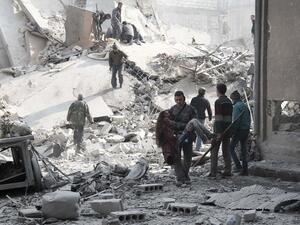 A volunteer from the Syrian Civil Defence (known as the White Helmets) carries a wounded girl after digging her out of the rubble following an air strike on Hamouria on January 9, 2018 (ABDULMONAM EASSA / AFP)