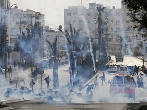 Palestinian protesters take cover from tear gas during clashes with Israeli forces on Jan. 12, 2018 north of Ramallah in the Israeli-occupied West Bank. 
ABBAS MOMANI / AFP