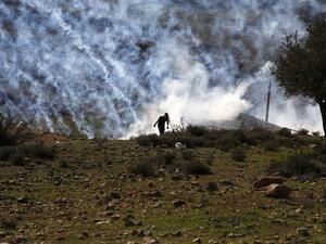 Palestinians run for covers from smoke-grenades during clashes with Israeli security forces following a demonstration in support of Palestinian prisoners on Jan. 13, 2018, in the West Bank village of Nabi Saleh (ABBAS MOMANI / AFP)