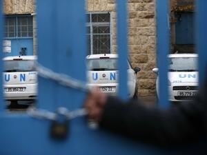 A Palestinian man holds a lock placed symbolically in protest around the main gate of the UNRWA office in the Israeli occupied West Bank city of Hebron on Jan. 17, 2018, after the White House froze tens of millions of dollars in contributions (HAZEM BADER / AFP)