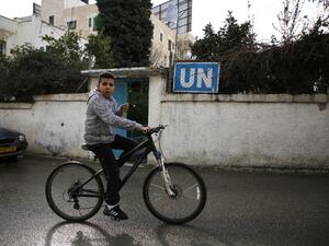 A Palestinian boy cycles past a United Nations' run health center in the Qalandia refugee camp near Ramallah in the West Bank, on Jan. 17, 2018 (ABBAS MOMANI / AFP)