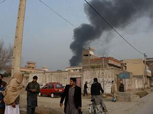 Afghan civilians gather on a street next to a plume of smoke coming from the area around an office of the British charity Save the Children during an ongoing attack in Jalalabad on Jan. 24, 2018 (NOORULLAH SHIRZADA / AFP)