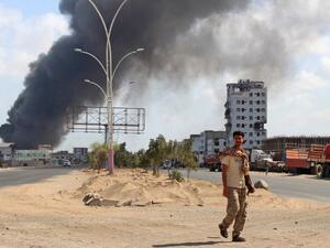 A fighters from the separatist Southern Transitional Council walks with smoke billowing in the background in the government's de facto capital Aden, as they move closer to taking full control of the southern city, on January 30, 2018 (SALEH AL-OBEIDI / AFP)