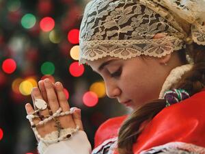 An Iraqi refugee prays during a Christmas service in Amman. (AFP/File)