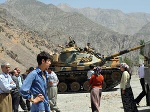 People stand near armored vehicles of Turkish military stationed in front of Gecimli military outpost where Kurdish rebels attacked and killed 6 soldiers and 2 village guard on 5 August in Hakkari. (AFP/File)