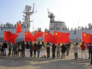 Chinese nationals living in Cyprus wave Chinese national flags as the Chinese frigate Yancheng comes in to dock at Limassol port, Jan. 4, 2014.