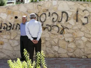 Arab Israeli men stand next to graffiti reading in Hebrew "Arabs Out" on the wall of a mosque in the northern Israeli city of Umm al-Faham. AFP Photo

