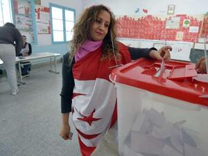 A Tunisian woman wearing the national flag casts her vote (AFP/File Photo)