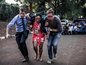 A woman is evacuated from the the hotel by two men during the terror attack on Tuesday afternoon which saw 21 civilians killed by the group of men linked to Al-Shabaab (AFP)