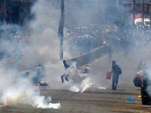 Palestinian men run for cover from tear gas thrown by Israeli forces (AFP/File Photo)