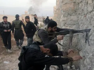 Syrian rebel fighters shoot through a hole in a wall towards forces loyal to the regime in Aleppo.(AFP / File)

