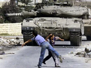 Young Palestinian boys throwing rocks, facing an Israeli tank, (AFP File Photo)