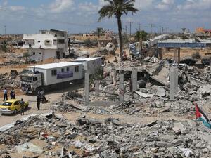 Trucks carrying mobile homes donated by Emirati charity Human Appeal International pass destroyed buildings in Khan Yunis' Khuzaa neighborhood in southern Gaza on September 13, 2014. (AFP/Said Khatib)
