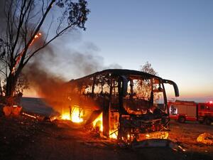 A picture taken on November 12, 2018 shows a bus set ablaze after it was hit by a rocket fired from the Gaza Strip, at the Israel-Gaza border near the kibbutz of Kfar Aza, on November 12, 2018 (AFP)