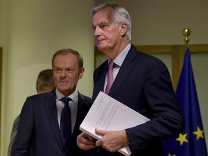 EU Brexit chief negociator Michel Barnier (R) holds the "draft agreement of the withdrawal of the United Kingdom of Great Britain and Northern Ireland from the European Union" while arriving with European Council President Donald Tusk for a press conference at the European Council in Brussels (AFP)