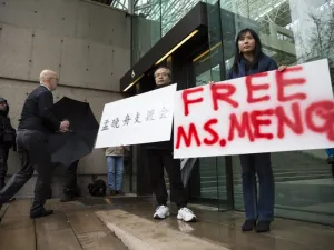 Robert Long (L) and Ada Yu hold signs in favor of Huawei Technologies Chief Financial Officer Meng Wanzhou outside her bail hearing at British Columbia Superior Courts following her December 1 arrest in Canada for extradition to the US, in Vancouver, British Columbia on December 11, 2018. 
Jason Redmond / AFP