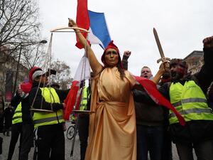 A woman, wearing a Phrygian cap to symbolically represent Justice, and yellow vest protestors 
Zakaria ABDELKAFI / AFP