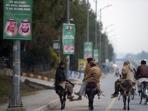 Pakistani labourers ride past welcoming posters featuring the portrait of Saudi Arabian Crown Prince Mohammed bin Salman on a street in Islamabad  (AFP)