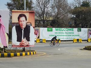 A foreigner rides past billboards showing portraits of Saudi Arabian Crown Prince Mohammed bin Salman (L) and Pakistan's Prime Minister Imran Khan (R) and a banner welcoming the prince ahead of his arrival in Islamabad  (AFP)