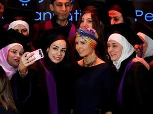 Syria's First Lady Asma al-Assad (centre) poses for a picture during a graduation ceremony of future teachers of a Syrian Organisation for Persons with Disabilities, in Damascus yesterday (Twitter)