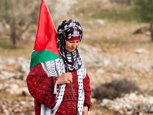 Palestinian woman walks with Palestinian flag during weekly demonstrations  (Shutterstock)