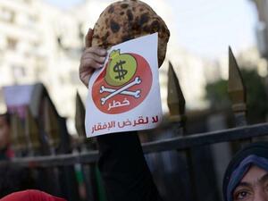 Egyptian protester holds bread along with a flyer in Arabic that reads 'Danger, no to loans that lead to poverty' during a rally in downtown Cairo on April 3, 2013. (AFP/Khaled Desouki)