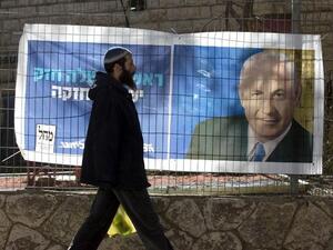 An Israeli settler walks past campaign posters of Israeli Prime Minister Binyamin Netanyahu at the Kiryat Arba settlement, in the Israeli occupied West Bank. (AFP PHOTO/MENAHEM KAHANA)