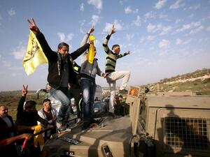 Palestinian protestors climb an Israeli military vehicle during a protest in Anin village in the West Bank near Jenin city. (AFP PHOTO/SAIF DAHLAH)