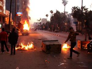 Egyptian anti-government protestors take cover behind burning dust bins during clashes with riot police. (AFP PHOTO / STR)
