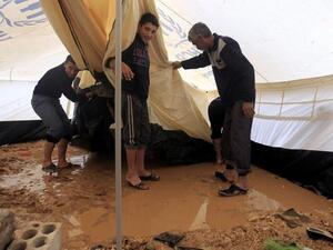 Syrian refugees try to remove water which had collected inside their tent after heavy rain in the Zaatari refugee camp. (AFP PHOTO/KHALIL MAZRAAWI)