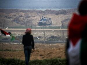 Gaza Strip east of Gaza City shows Palestinians protesting with Palestinian flags by the barbed-wire fence along the border with Israel, with an Israeli army vehicle seen across on the other side. (Said KHATIB / AFP)