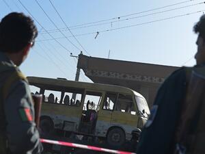 Afghan policemen look at the site of a suicide attack to have hit a minibus carrying foreign security guards in Kabul on June 20, 2016. (AFP/Shah Marai)