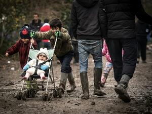 A young boy pushes his sibling through the mud at a makeshift camp close to Calais.0 (AFP/File)