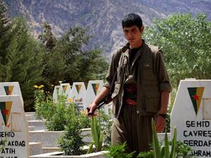 A member of the Kurdistan Workers' Party (PKK) walks past graves at a cemetary on July 29, 2015 deep in the Qandil mountain, the PKK headquarters in northern Iraq (AFP/Safin Hamed)