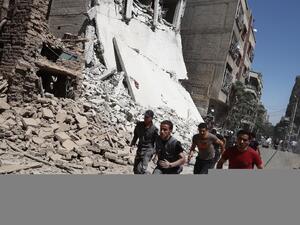 Syrians run for cover during reported government air strikes in the rebel-held town of Douma, east of the capital Damascus. (AFP/Abd Doumany)