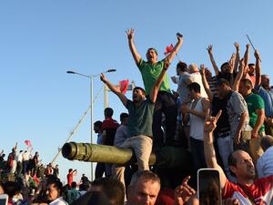People react after taking over military position on the Bosphorus bridge in Istanbul, on July 16, 2016 (AFP/Bulent Kilic)