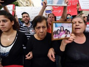 The mother of Roula Yacoub, a victim of domestic violence, holds a portrait of her deceased daughter during a rally on "International Women's Day" on March 8, 2014 in front of the National Museum in Beirut, Lebanon. (AFP/File)