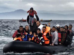 A man holds up a young boy as a boat carrying refugees arrives at the Greek island of Lesbos after crossing the Aegean Sea from Turkey. (AFP/File) 