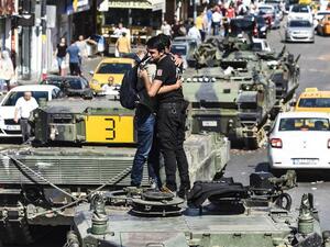 A police officer embraces a man on abandoned tank at Uskudar in Istanbul Saturday. (AFP/Bulent Kilic) 