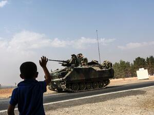 A Turkish boy waves to Turkish tank convoy driving into Syria from the border city of Karkamis in the southern region of Gaziantep, on August 26, 2016. (AFP/Bulent Kilic)