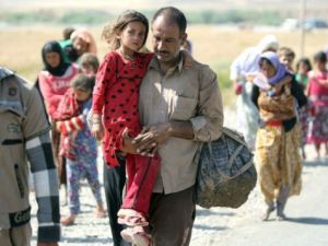 A displaced Iraqi man from the Yazidi community carries his daughter as they cross the Iraqi-Syrian border at the Fishkhabur crossing, in northern Iraq, on August 11, 2014. (AFP/Ahmad Al-Rubaye)